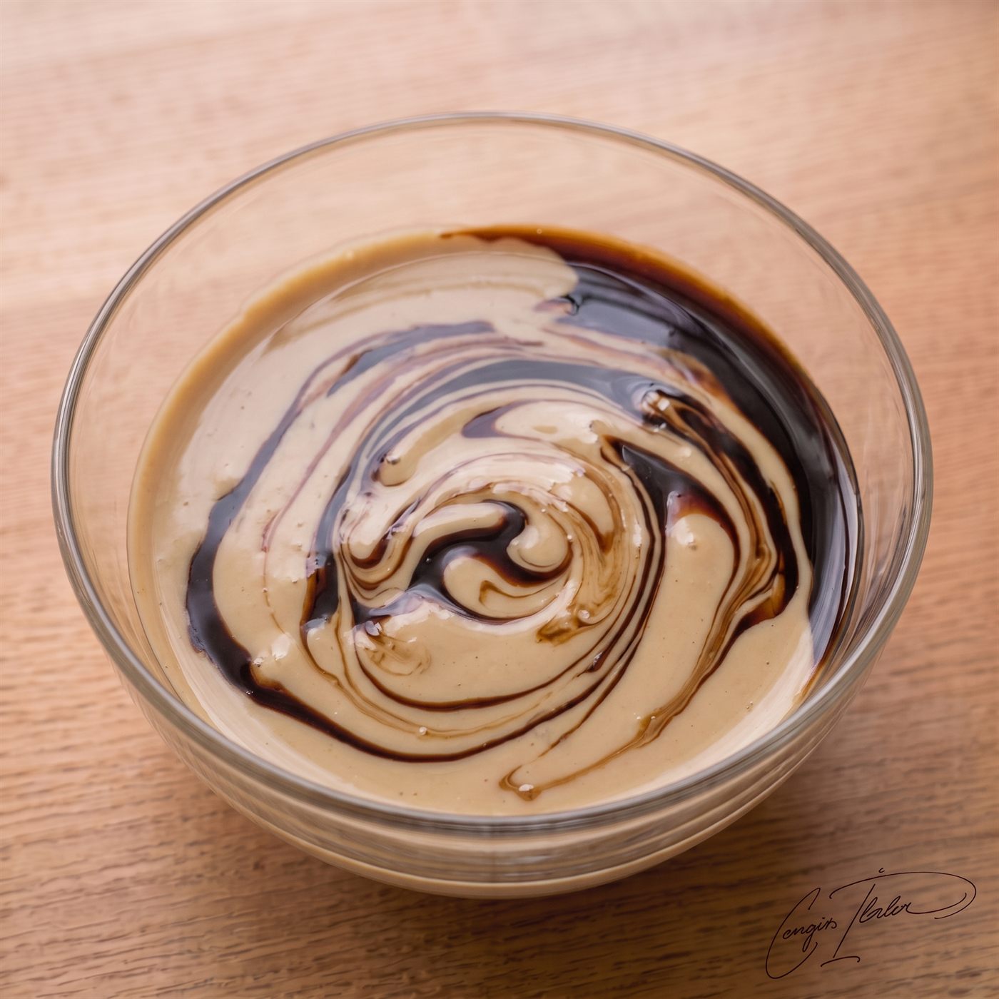 A glass bowl containing a hypnotic, swirled mixture of pale tahini and dark, rich grape molasses.