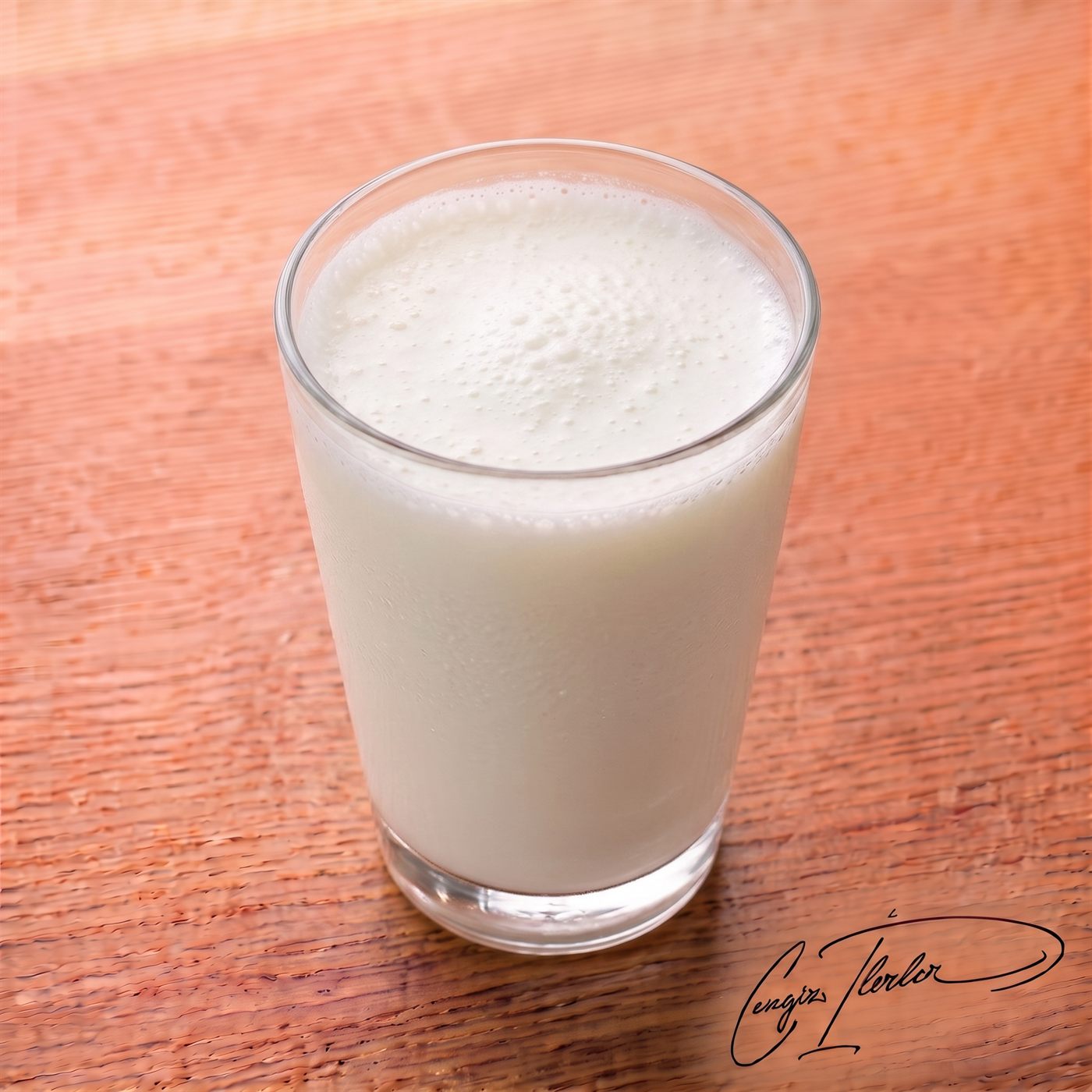 A tall glass of frothy ayran — the salted yogurt drink — with a foamy white top.