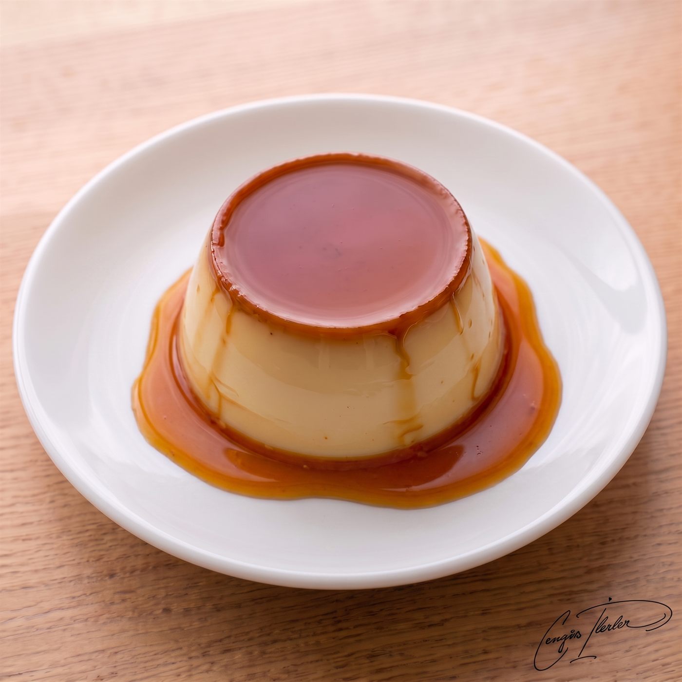 An inverted cream caramel on a white plate, amber caramel running down its sides.