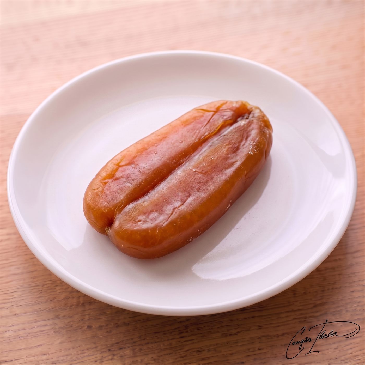 A whole lobe of bright orange cured fish roe (bottarga) resting on a small white plate.