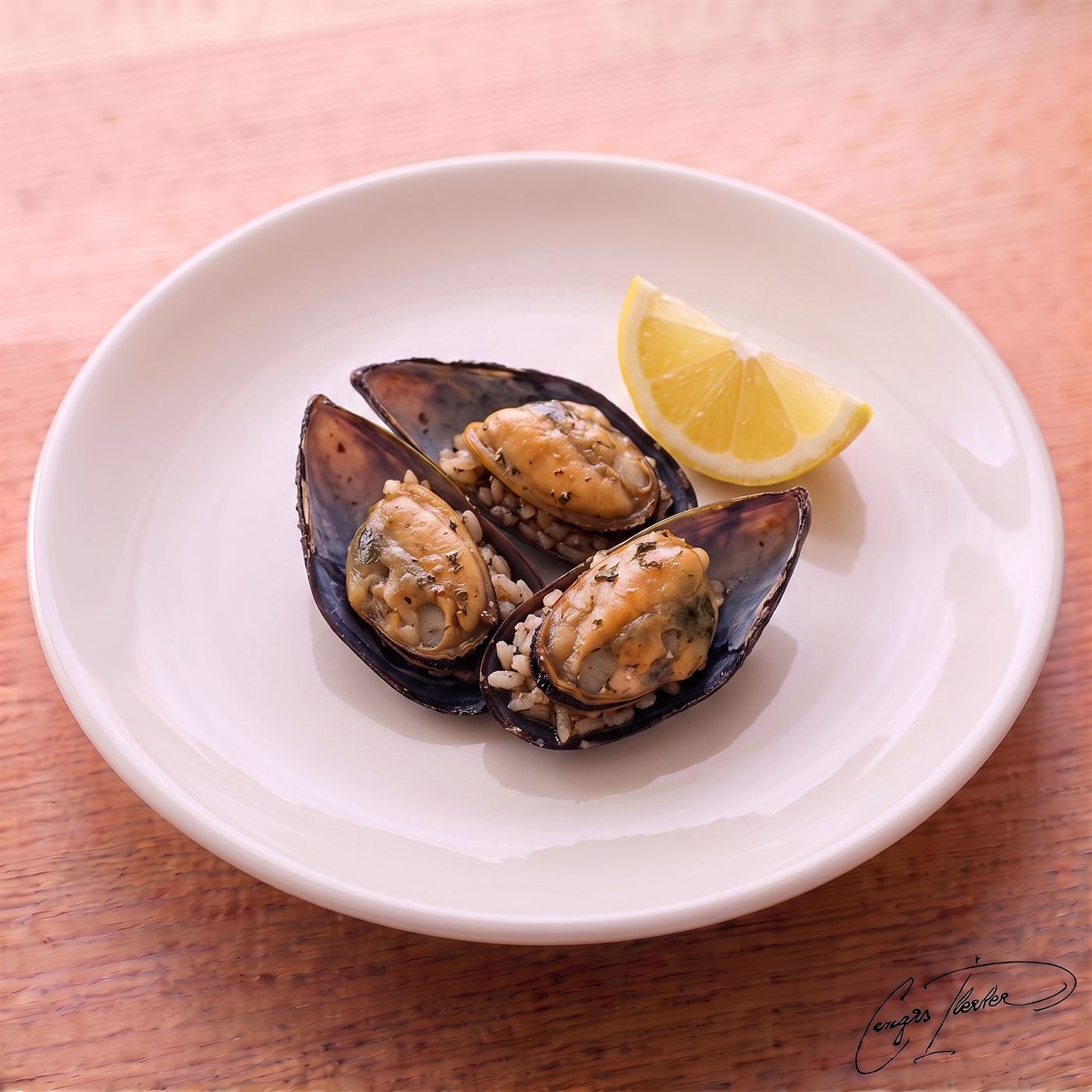 A white plate holding three midye dolma (stuffed mussels) — their dark shells opened to reveal a savory, spiced rice filling — served with a wedge of fresh lemon.